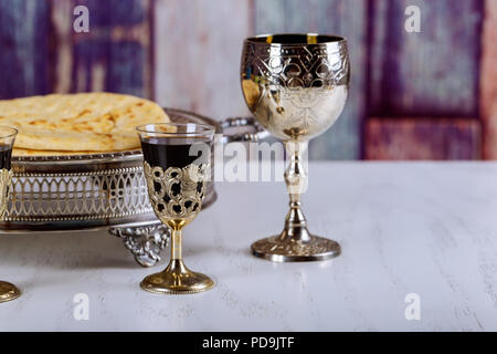 Die Gemeinschaft. Schale aus Glas mit Rotwein, Brot auf Holztisch close-up. Fokus auf Wein Stockfoto