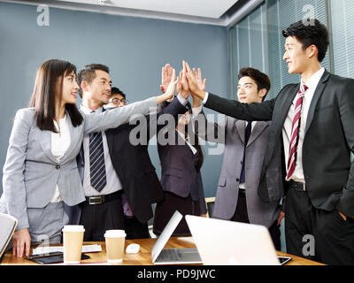 Team von Asian Business Leute, Männer und Frauen die Hände zusammen, Entschlossenheit und Geschlossenheit zu zeigen. Stockfoto