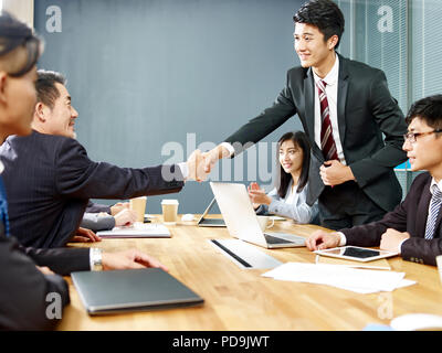 Zwei asiatischen Führungskräfte Hände schütteln über Verhandlungstisch. Stockfoto