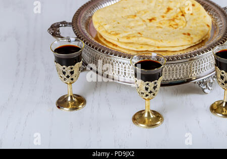 Die heilige Kommunion in der Kirche, Schale aus Glas mit Rotwein, Brot auf Holztisch. Christen Symbole Konzept. Stockfoto