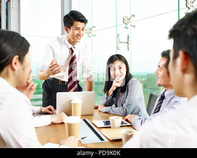 Junge asiatische Geschäftsmann sprechen mit Kollegen während der Sitzung im modernen Büro. Stockfoto