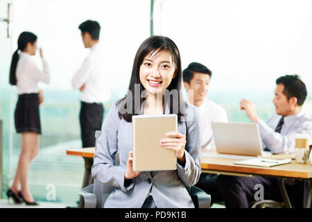 Portrait von jungen asiatischen Business woman holding digital Tablet auf Kamera lächelnd im Büro. Stockfoto