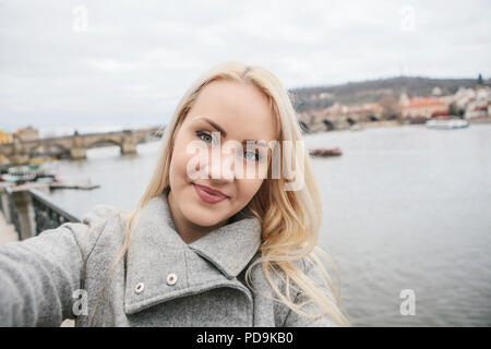 Eine schöne, junge blonde Frau oder touristische selfie tun oder sich selbst fotografieren in Prag in der Tschechischen Republik. Charles Bridge im Hintergrund. Stockfoto