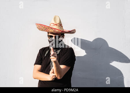 Junge männliche Person gekleidet in traditionelle Sombrero, bandana und Sonnenbrillen. Mexikanische festliche oder Halloween Konzept des Menschen als Bandit oder westlichen Posing Stockfoto