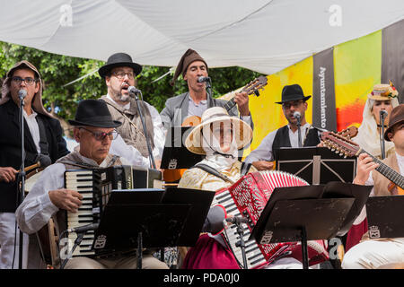 Folk Musiker mit accordians, timples und Gitarren, in der Tracht gekleidet, spielen auf der Bühne für den Tag der Kanaren, Alcala, Teneriffa, Ca Stockfoto