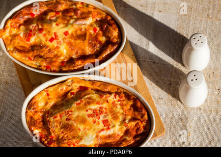 Zwei Fächer mit gebackenen Omelette aus Käse, Eier, Schinken und rotem Pfeffer auf dem Tisch gemacht Stockfoto