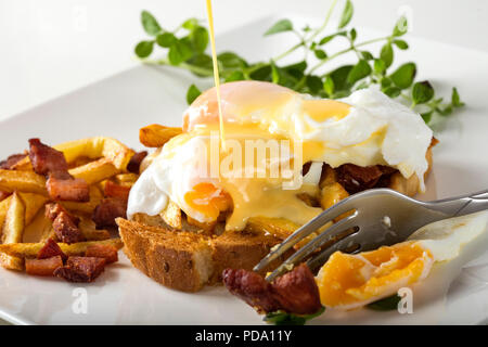 Toast Sandwich mit zwei pochierte Eier, Pommes frites und Speck auf der Platte Stockfoto