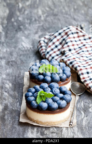 Zwei mini Schokolade Käsekuchen mit frischen Heidelbeeren auf hölzernen Tisch Stockfoto