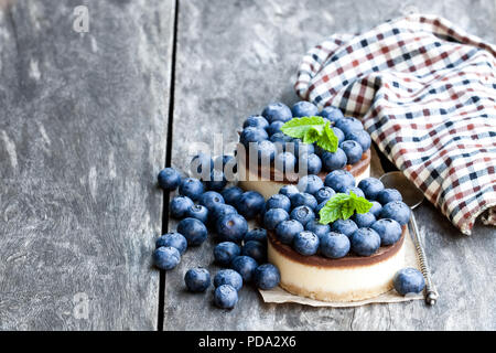 Zwei mini Schokolade Käsekuchen mit frischen Heidelbeeren auf hölzernen Tisch Stockfoto