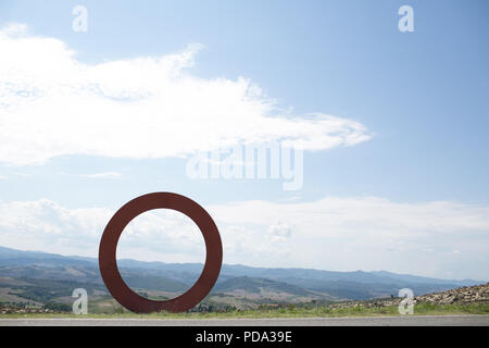 Große rote Kreis Skulptur von Mauro Staccioli in der Nähe der Straße auf dem Weg nach Volterra, Toskana, Italien Stockfoto