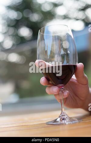 Nahaufnahme eines Menschen Hand hält ein Glas Rotwein. Stockfoto