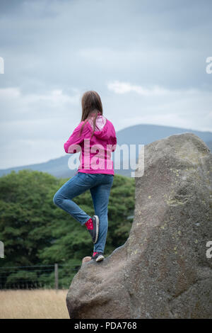 Junger Teenager steht auf einem großen Stein auf Castlerigg Steinkreis, Cumbria, Großbritannien in einem zen wie darstellen, zurück zu Kamera aufsaugen der Atmosphäre. Stockfoto