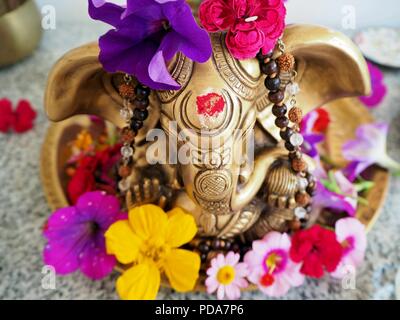 Hindu Gott Ganesha ist mit farbigen Blumen auf dem Altar für einen Spirituellen Zeremonie abgedeckt Stockfoto