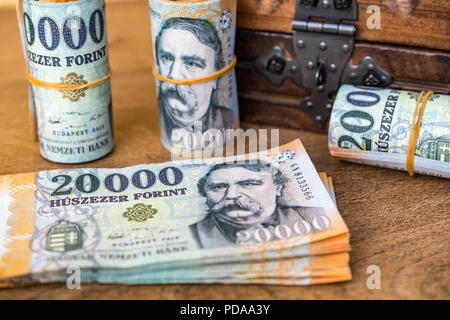 Stapel von Ungarischen Geld (Forint) und aufgerollt 20000 Forint Banknoten mit einem geschlossenen vintage Holzkiste im Hintergrund Stockfoto