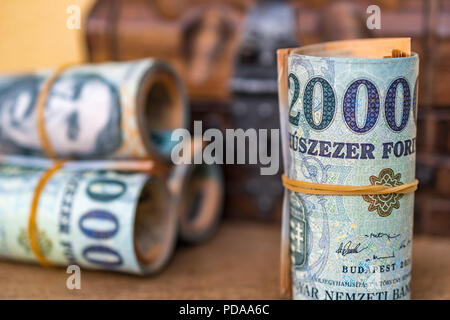 Aufgerollt und 20000 Forint Banknoten gestapelt mit einem geschlossenen vintage Holzkiste im Hintergrund Nahaufnahme Stockfoto