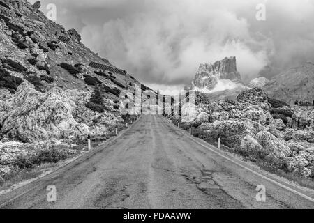 Leere verlassenen Straße in Schwarz und Weiß zu bedrohlichen stürmischen, bewölkt Berge der Dolomiten, Italien Stockfoto