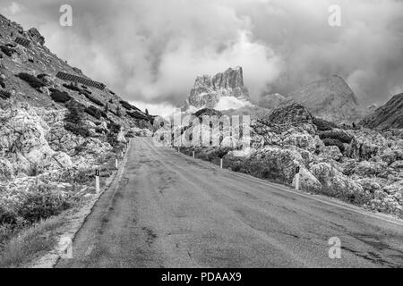 Leere verlassenen Straße in Schwarz und Weiß zu bedrohlichen stürmischen, bewölkt Berge der Dolomiten, Italien Stockfoto