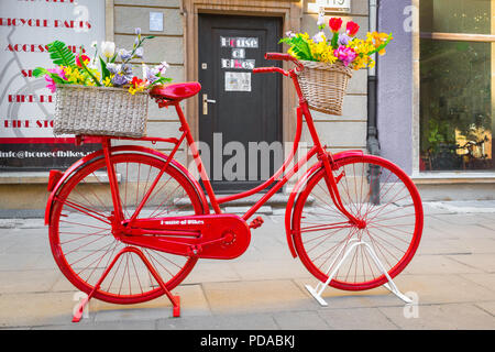 Rotes Fahrrad, Blick auf ein Vintage-Fahrrad gespritzt leuchtend rot vor einer Fahrradwerkstatt in einer Straße in Danzig, Polen. Stockfoto