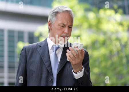 Nachdenklich Geschäftsmann an seinem Handy suchen Stockfoto