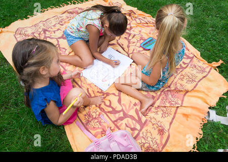 Kinder Zeichnung auf einem Notebook während in einem Park Stockfoto