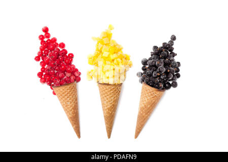 Verschiedene Eissorten Aroma in der Kegel Gefrorene Beeren, Mango, Ananas, rote und schwarze Johannisbeeren auf weißem Hintergrund. Sommer kreatives Konzept. Stockfoto