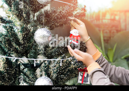 Little boy Weihnachtsbaum mit Weihnachtsmann Puppen Dekoration im Sonnenlicht zu verzieren. Stockfoto