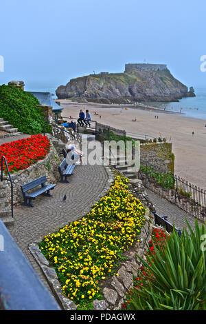 Die Aussicht auf South Beach in Richtung St Catherine's Island oder Fort, Tenby, W. Wales. Hübsche Blumen im Vordergrund. Stockfoto