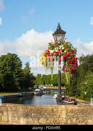 Boote auf der Themse in Abingdon Oxfordshire aus dem Fluss Brücke gesehen mit alten Lamp Post und floralen hängende Körbe Stockfoto