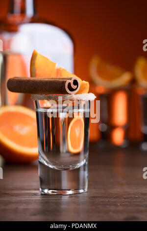 Gläser tequila mit Orange und Zimt Sticks auf einen hölzernen Tisch. Stockfoto