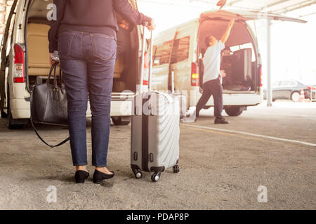Frau touristische stehend mit Gepäck mit Abholung Van am Flughafen. Stockfoto