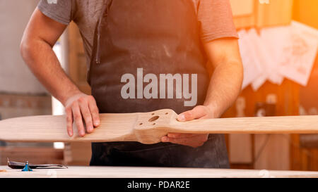 Erfahrene Tischler in Arbeitskleidung und kleine Steuerungsfunktionen für Eigentümer in Holzarbeiten, holding Holz, auf Hintergrund Arbeitstisch in der Werkstatt Stockfoto