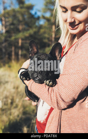 Junge blonde Frau mit französischen buldog Welpen und genießen Sie in sonniger Tag. Stockfoto