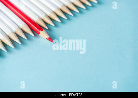 Business-Konzept - viele weiße Bleistifte und Farbstift auf blauem Papierhintergrund. Es ist Symbol für Kampf, Führung und Kommunikation. Stockfoto