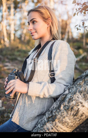 Schöne blonde Frau auf der Suche durch ein Fernglas und Blick auf die traumhafte Landschaft und den Sonnenuntergang. Stockfoto