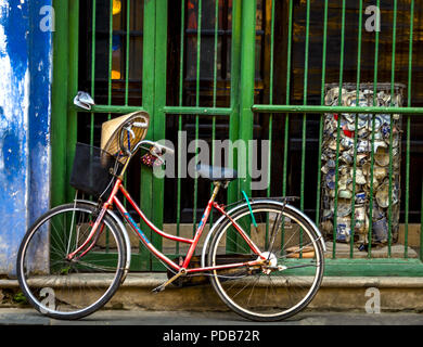 Fahrrad geparkt in der Alten Stadt Hoi An einer Wand entlang und und einen grünen Balken. Stockfoto