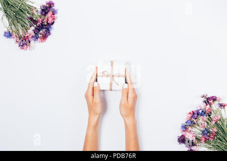 Woman's Hände, die kleine Box neben Blumensträuße von bunten Kornblumen, flach. Frauen, die eine unter Floral frame auf weißem backgroun Stockfoto