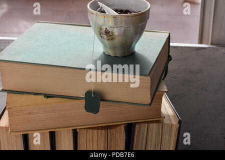 Eine Tasse Kaffee auf dem Stapel der alten staubigen Bücher Stockfoto