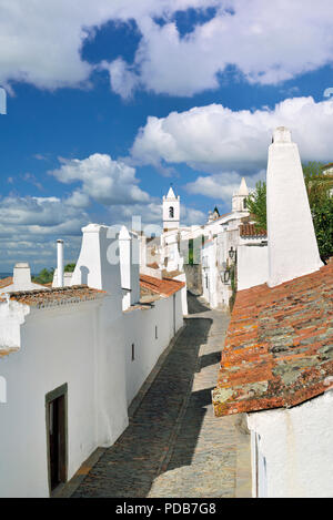 Charmante mittelalterliche Gasse mit weiß getünchten Häusern und dramatische Wolkenhimmel mit Sun Stockfoto