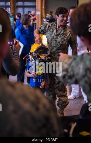 180802-N-SH 284-0162 SEATTLE (August 02, 2018) Navy Diver 2. Klasse Tyler McLaughlin hilft einem Kind versuchen, auf einen Tauchgang Helm auf eine statische Darstellung von der Naval Station Everett dive locker im Seattle Aquarium während der 69. jährlichen Seafair Flotte Woche präsentiert. Seafair Fleet Week ist eine jährliche Feier des Meeres Dienstleistungen darin Seemänner, Marinesoldaten und Küstenwache Mitglieder vom Besuch der US-Marine und Küstenwache Schiffe und Schiffe aus Kanada machen die Stadt zu einem Hafen des Anrufs. (U.S. Marine Foto von Mass Communication Specialist 2. Klasse Vaughan Dill/Freigegeben) Stockfoto