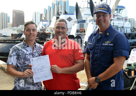 Die Eigentümer des Schiffes Namahoe erhalten neue des Schiffes Kontrollbescheinigung, die Ihnen von Chief Warrant Officer Bryan Anderson in Honolulu, Aug 2, 2018 ausgestellt. Die Kontrollbescheinigung war die erste in der Coast Guard 14. Bezirk nach der Umsetzung der neuen Vorschriften, 20. Juli 2018 ausgestellt werden. (U.S. Coast Guard Foto von Petty Officer 3. Klasse Matthew West/Freigegeben) Stockfoto