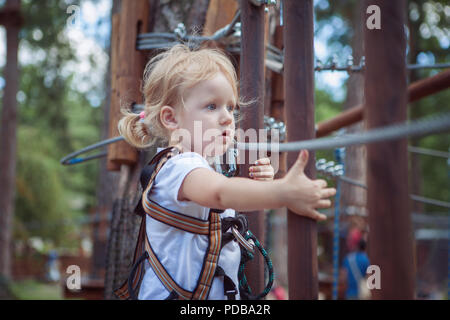 Mädchen in der Ausrüstung, überwindet das Hindernis in den Seilpark. Stockfoto