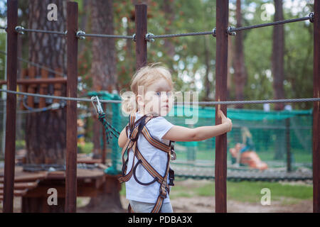 Porträt eines kleinen Mädchens im Seilpark. Sie überwindet das Hindernis. Stockfoto