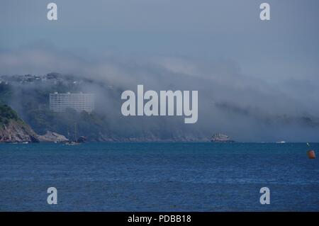 Advektion Meer Nebel über Felsen und Hotel durch das blaue Meer. Englische Riviera, Torquay. Juni, 2018. Stockfoto