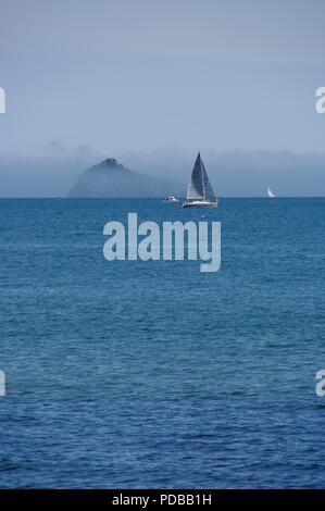 Freude Yacht Segeln auf blauem Meer von Thatcher Rock, durch Advektion Meer Nebel verdeckt werden. Englische Riviera, Torquay. Juni, 2018. Stockfoto