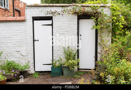 Ein alter gemauerter Schuppen mit zwei schwarzen und weißen Türen lackiert Stockfoto