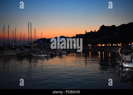 Helles Orange Sonnenuntergang im Meer Reflektieren über Baska Voda Hafen Kroatien mit Silhouettiert Yachten und Boote Stockfoto