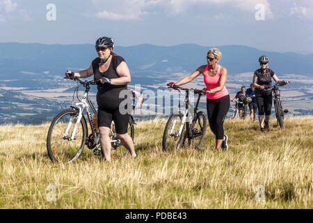 Frauen fahren Fahrrad, Radfahrer fahren auf einem Bergweg, Velka Javorina Berg, tschechische slowakische Grenze in den Weißen Karpaten Frauen, die einen Berg hinaufschieben Stockfoto