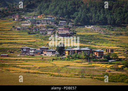 Ansicht der Bhutanesischen Dorf und Bauern mit der Ernte der Reisfelder, Bhutan. Stockfoto