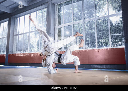 Zwei judo Kämpfer zeigt technische Fertigkeit beim Üben der Kampfkunst in einem Fight Club. Die beiden passen Männer in Uniform. kämpfen, Karate, Ausbildung, Kunst, Athlet, Wettbewerb Konzept Stockfoto