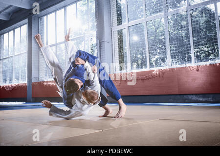 Zwei judo Kämpfer zeigt technische Fertigkeit beim Üben der Kampfkunst in einem Fight Club. Die beiden passen Männer in Uniform. kämpfen, Karate, Ausbildung, Kunst, Athlet, Wettbewerb Konzept Stockfoto